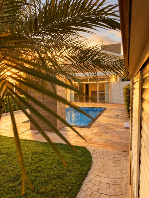 Jardim com palmeira ao lado da piscina, casa à venda no Condomínio Magnólias I em Araraquara